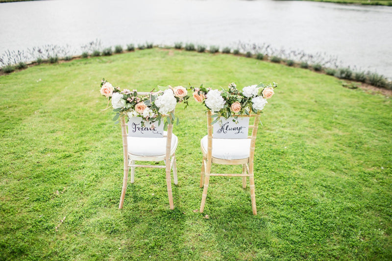 Two decorated chairs at an outdoor wedding, personalized wedding gifts