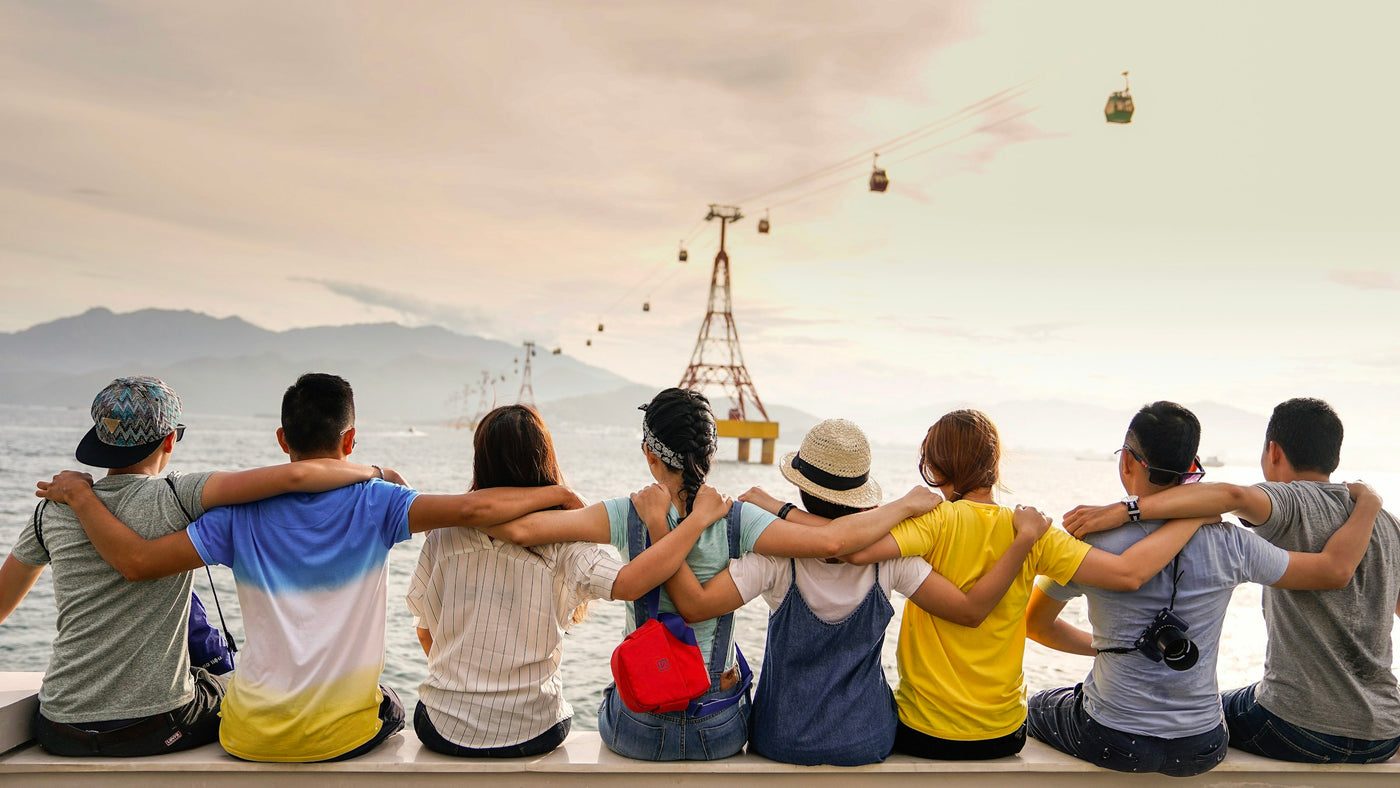 Friends in colorful personalized t-shirts with their arms around each other at sunset